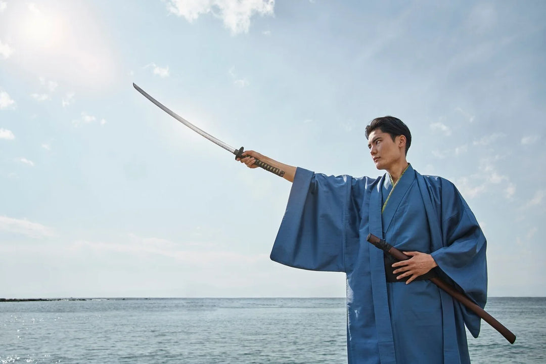 man wearing a blue kimono on a beach