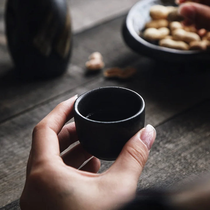 woman holding a cup from a japanese sake drink set